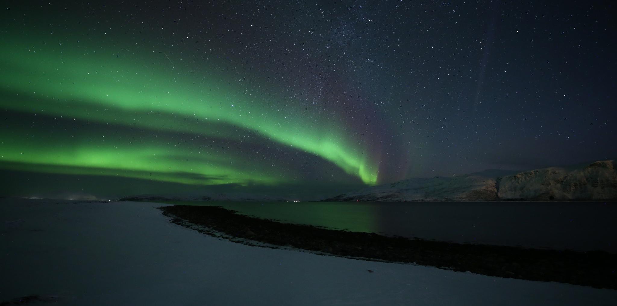 挪威一座城市上空，黑暗的天空中闪烁着波浪形的绿光. 