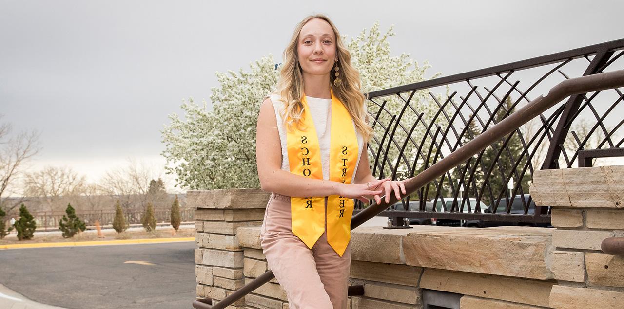 Madeline Dannewitz wearing a yellow ribbon standing on steps outside