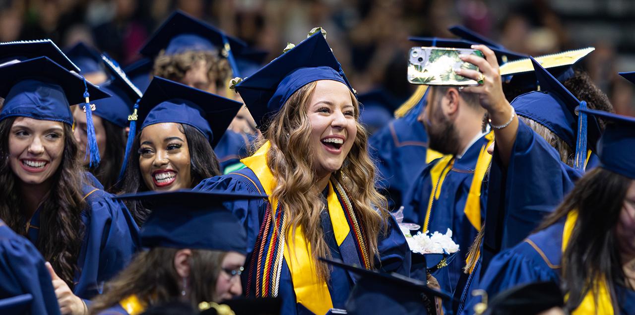 一群博天堂官方的学生在毕业典礼上戴着帽子，穿着长袍，微笑着站在那里自拍